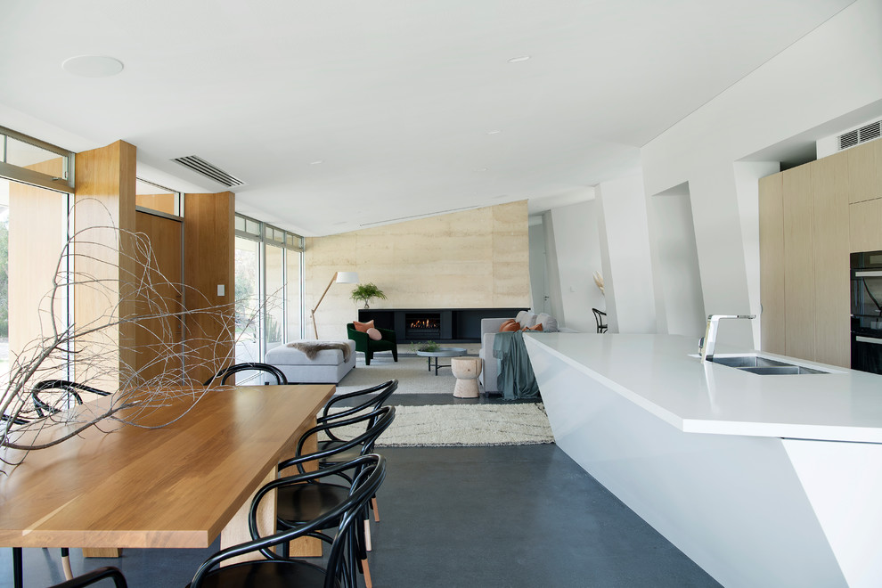 Esempio di una sala da pranzo aperta verso il soggiorno design con pareti bianche, pavimento in cemento e pavimento grigio