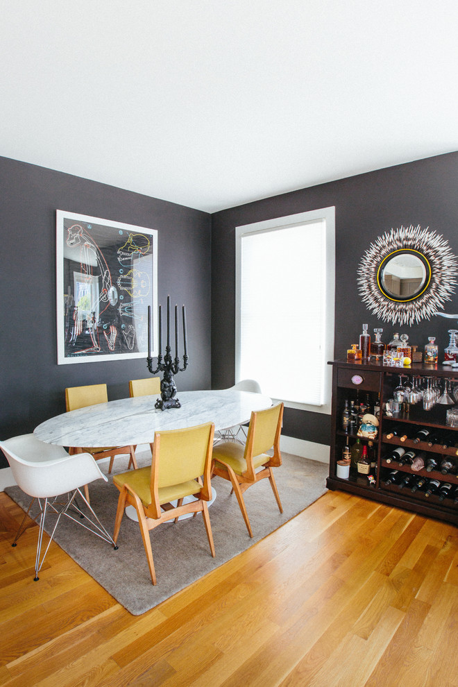 Foto di una sala da pranzo aperta verso il soggiorno contemporanea con pareti nere e pavimento in legno massello medio