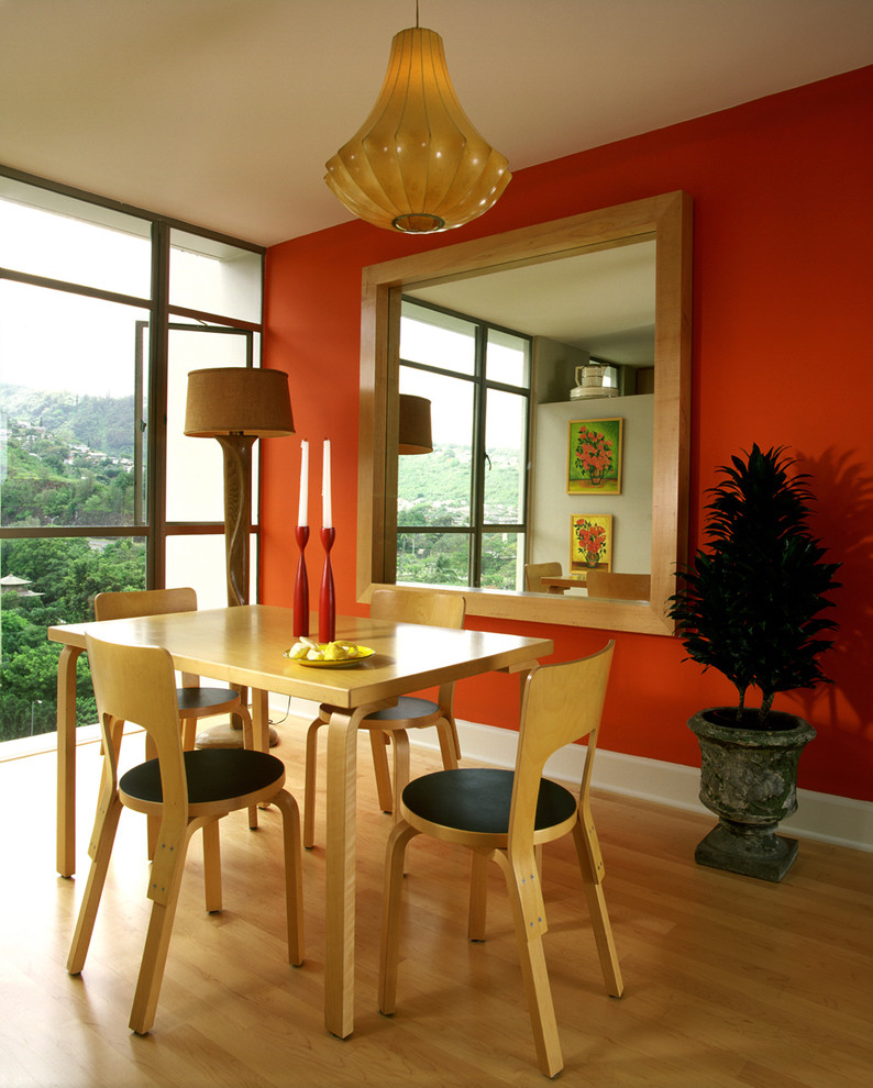 Diseño de comedor actual con paredes rojas y suelo de madera en tonos medios