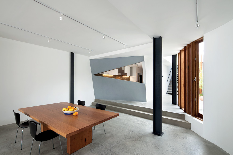 This is an example of a contemporary open plan dining room in Melbourne with white walls and concrete flooring.