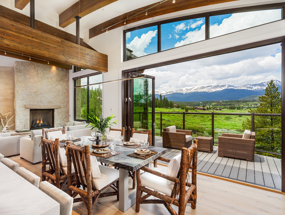 This is an example of a contemporary open plan dining room in Denver with white walls, light hardwood flooring, a standard fireplace and a stone fireplace surround.