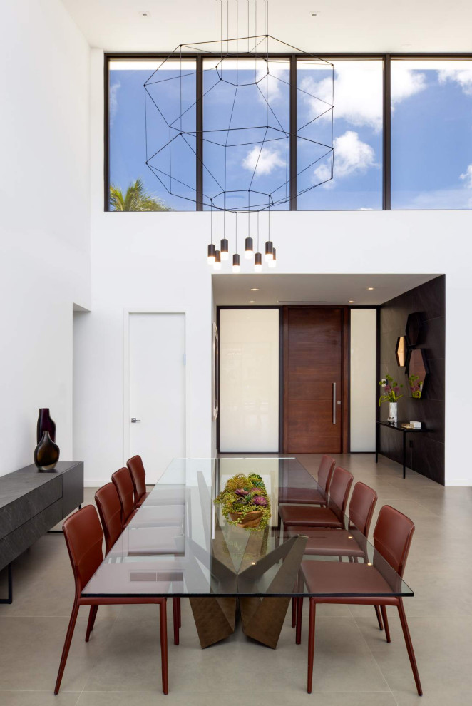 Réalisation d'une salle à manger ouverte sur le salon design avec un mur blanc, sol en béton ciré et un sol gris.