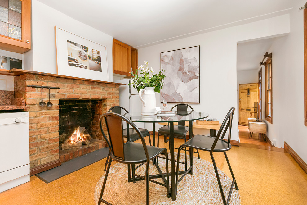 Idées déco pour une salle à manger ouverte sur la cuisine contemporaine avec un mur blanc, une cheminée standard, un manteau de cheminée en brique et un sol marron.