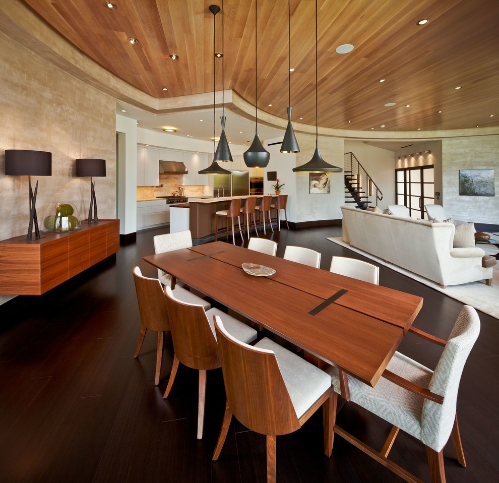Exemple d'une salle à manger ouverte sur le salon tendance avec un mur beige, parquet foncé, aucune cheminée et éclairage.
