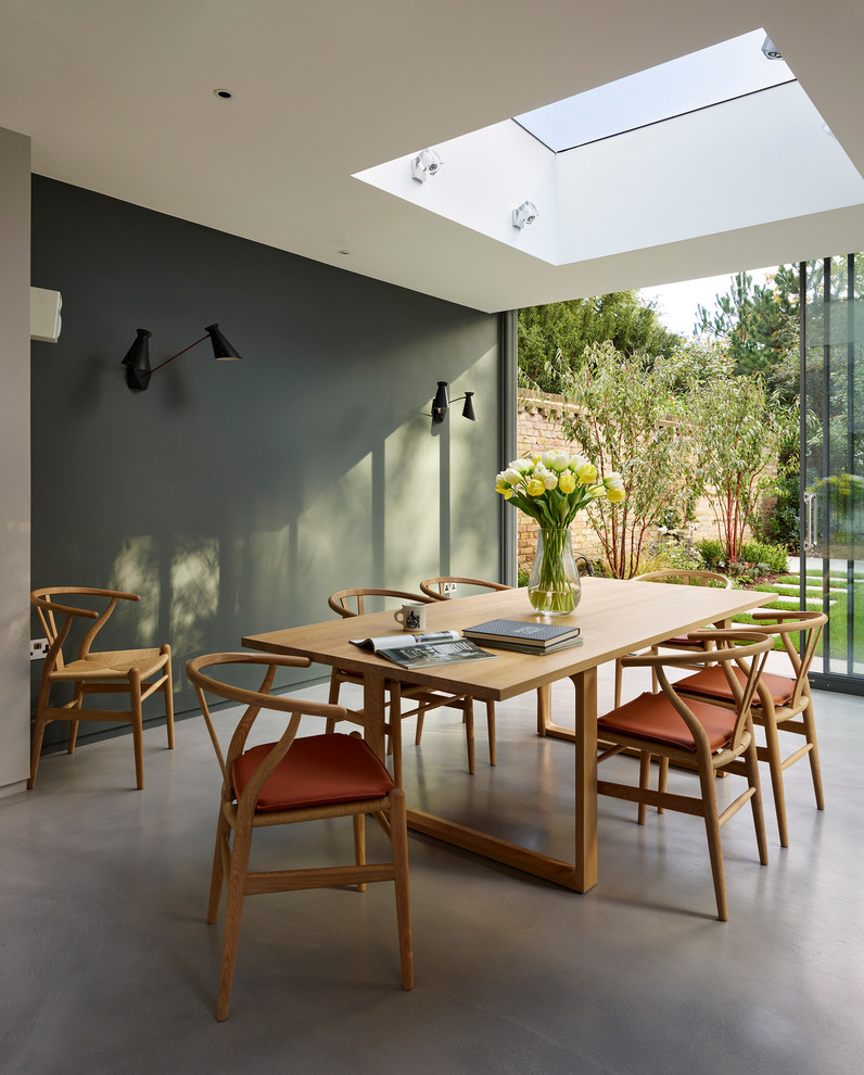 Idée de décoration pour une salle à manger design avec sol en béton ciré et un mur gris.