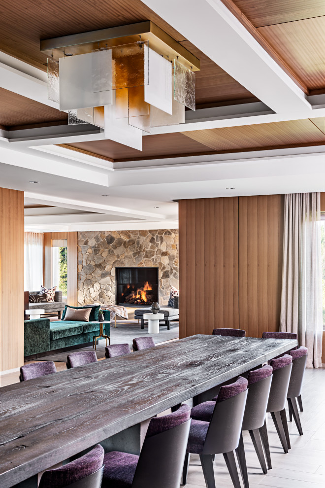 Cette image montre une grande salle à manger ouverte sur le salon design avec un mur marron, parquet clair, aucune cheminée et un sol marron.