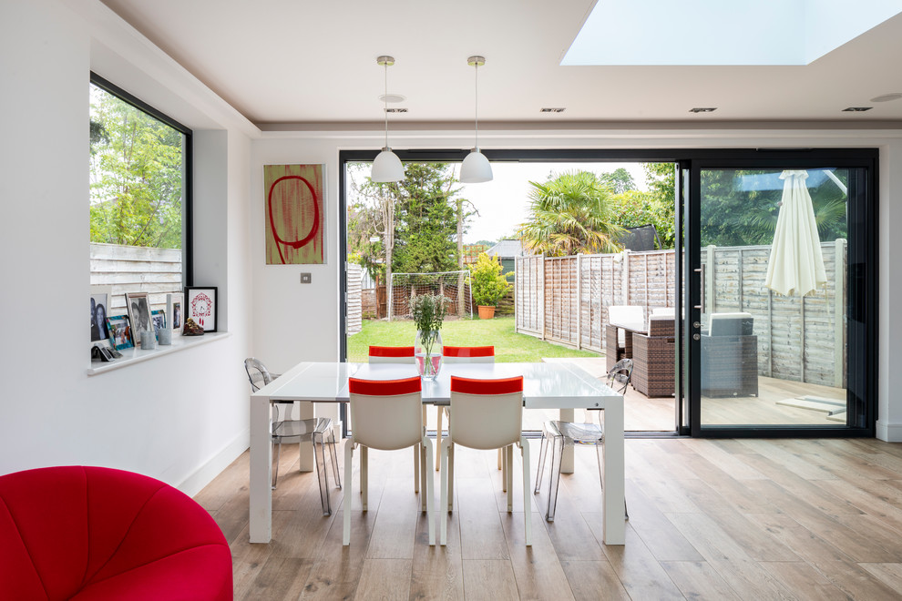 Photo of a medium sized contemporary dining room in London with white walls, light hardwood flooring and brown floors.