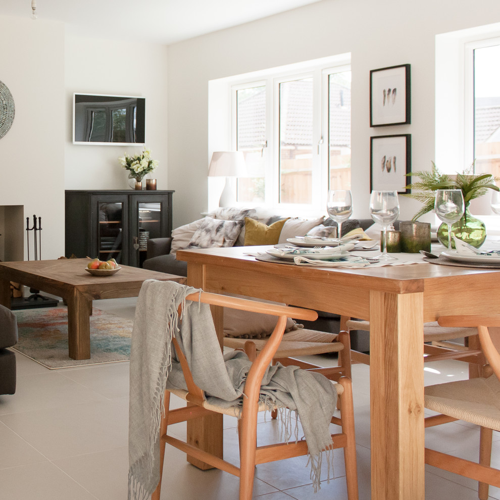 Cette photo montre une salle à manger ouverte sur la cuisine moderne de taille moyenne avec un mur blanc, un sol en carrelage de porcelaine, un poêle à bois, un manteau de cheminée en plâtre, un sol beige et éclairage.
