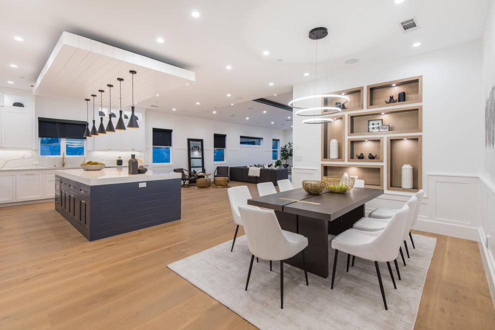 Large contemporary kitchen/dining room in Los Angeles with white walls, medium hardwood flooring, beige floors and wainscoting.