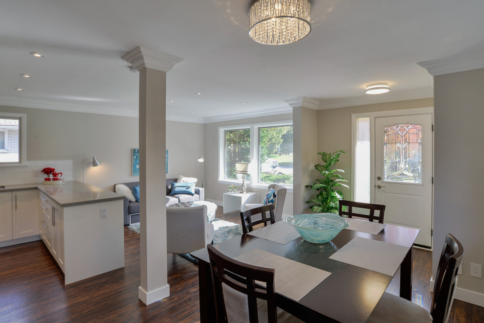 Immagine di una sala da pranzo aperta verso il soggiorno minimalista di medie dimensioni con pavimento in laminato, pavimento marrone, pareti beige e nessun camino