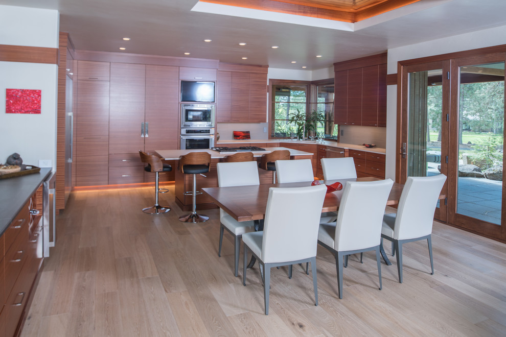 Immagine di una sala da pranzo aperta verso la cucina minimal di medie dimensioni con pareti bianche, parquet chiaro, camino classico e cornice del camino in legno