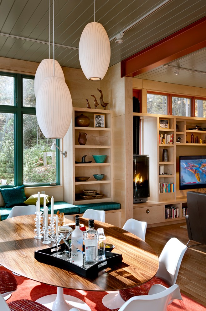 Idee per una sala da pranzo aperta verso il soggiorno contemporanea con pavimento in legno massello medio e stufa a legna