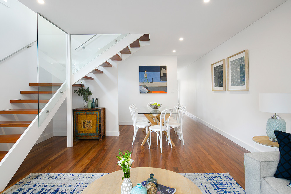 Photo of a medium sized contemporary dining room in Sydney with white walls, no fireplace, brown floors, medium hardwood flooring and feature lighting.