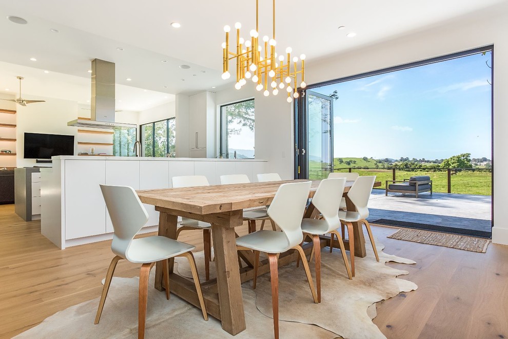 Idée de décoration pour une salle à manger ouverte sur la cuisine design avec un mur blanc, un sol en bois brun et un sol marron.