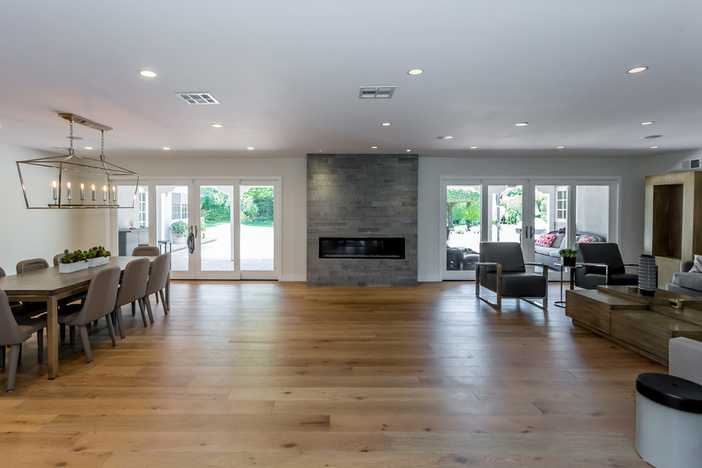 Photo of a large contemporary open plan dining room in San Francisco with white walls, medium hardwood flooring, a standard fireplace, a tiled fireplace surround and brown floors.