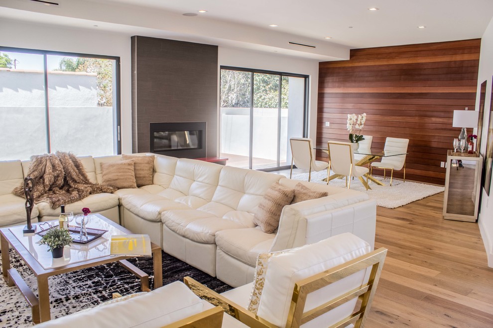 Example of a small trendy medium tone wood floor and brown floor great room design in Los Angeles with white walls, a ribbon fireplace and a metal fireplace