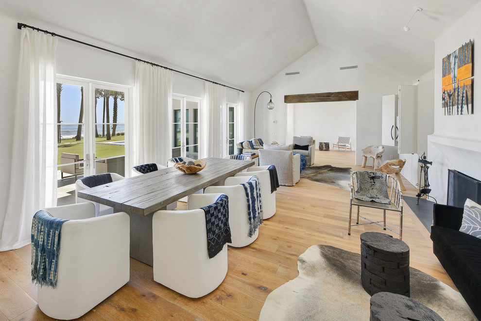Exemple d'une salle à manger ouverte sur le salon tendance avec un mur blanc, parquet clair, une cheminée standard et un manteau de cheminée en plâtre.