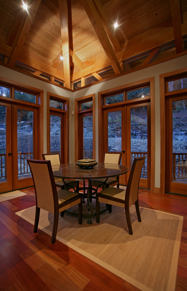 Cette image montre une grande salle à manger ouverte sur le salon craftsman avec un mur blanc et un sol en bois brun.