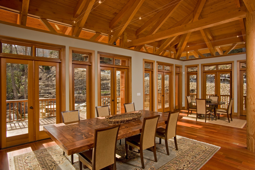 Aménagement d'une grande salle à manger ouverte sur le salon craftsman avec un mur blanc, un sol en bois brun et aucune cheminée.