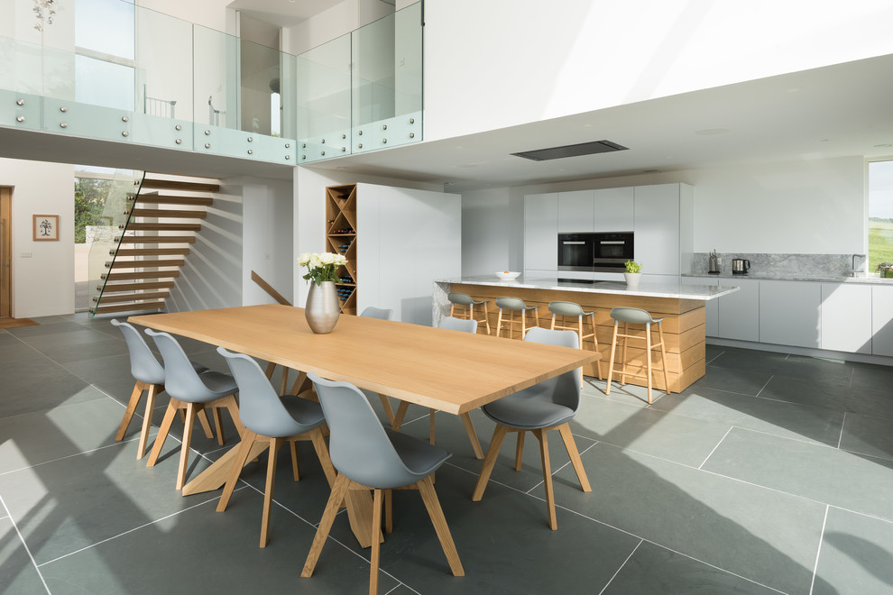 Design ideas for a large contemporary open plan dining room in Cornwall with white walls and grey floors.
