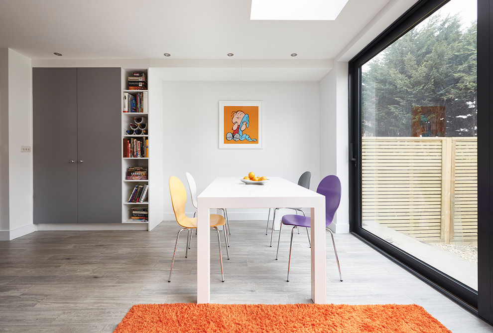 This is an example of a medium sized contemporary enclosed dining room in London with white walls and grey floors.