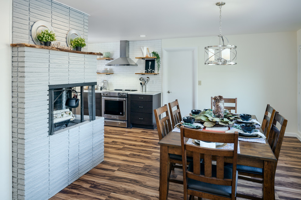 Foto de comedor de cocina actual pequeño con paredes blancas, suelo laminado, chimenea de esquina, marco de chimenea de ladrillo y suelo multicolor