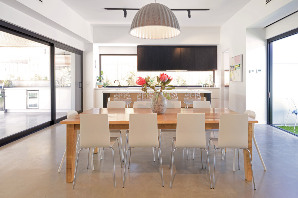 Esempio di una grande sala da pranzo aperta verso il soggiorno minimal con pavimento in cemento e pavimento grigio