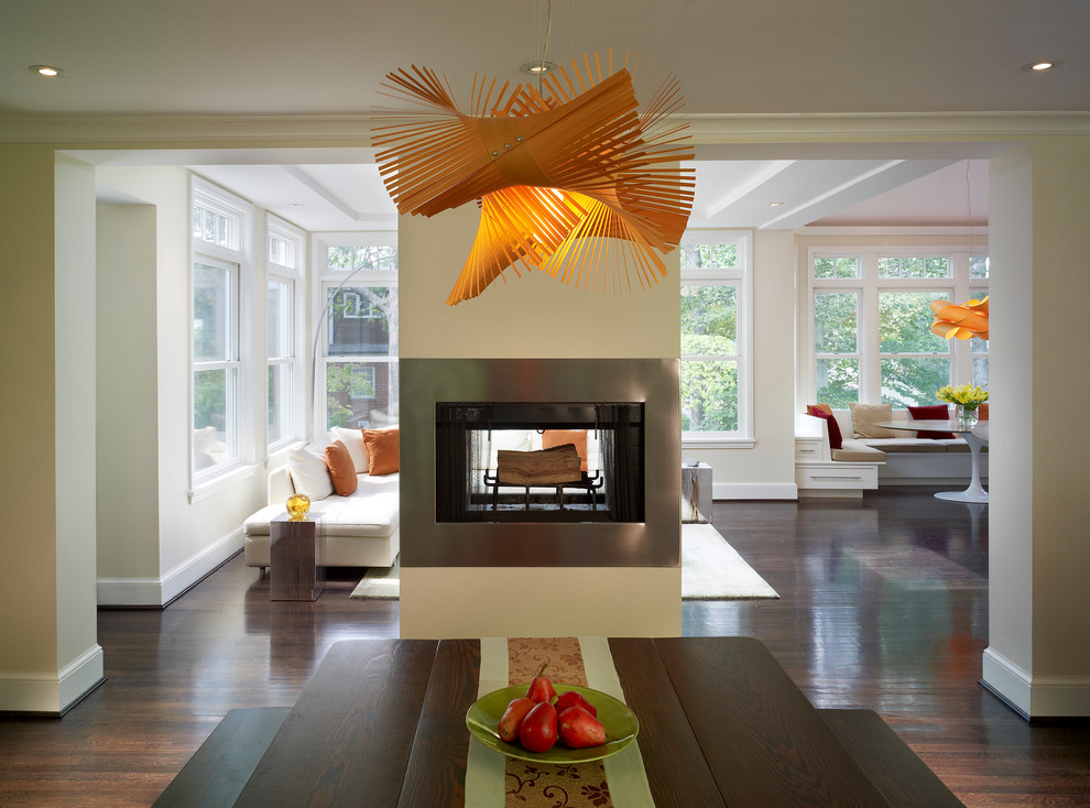This is an example of a contemporary dining room in DC Metro with a two-sided fireplace and a metal fireplace surround.