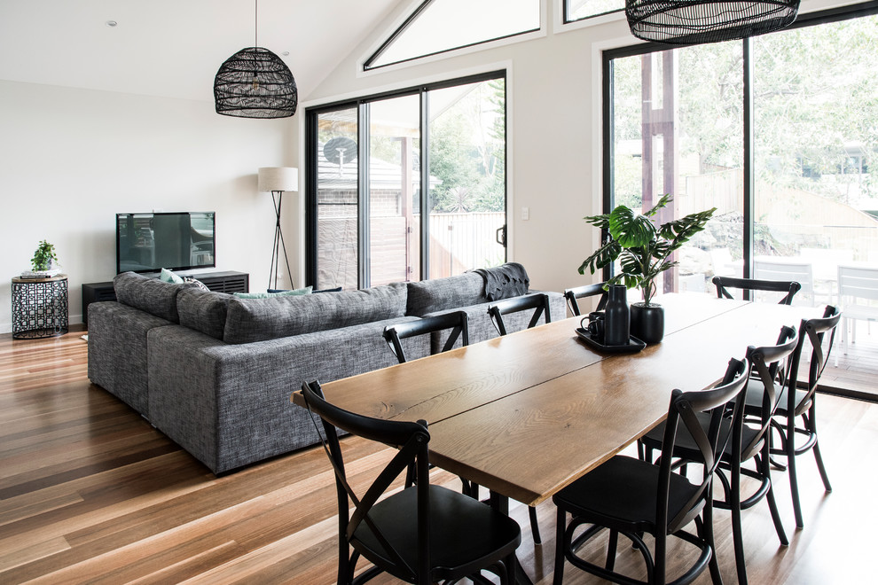 Foto di una grande sala da pranzo aperta verso il soggiorno contemporanea con pareti bianche e pavimento in legno massello medio