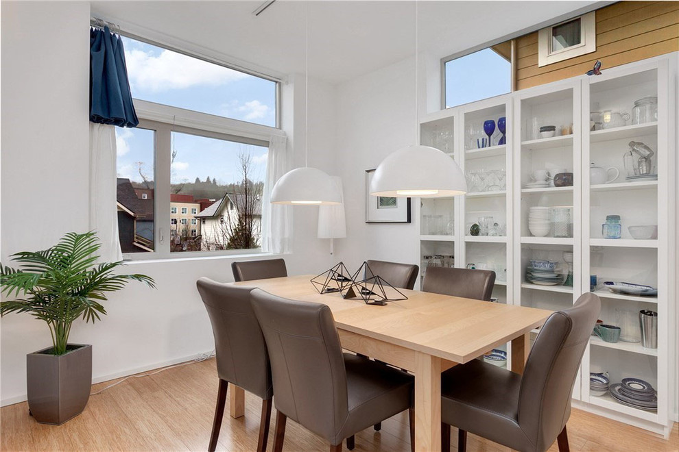 This is an example of a medium sized contemporary open plan dining room in Seattle with white walls and light hardwood flooring.