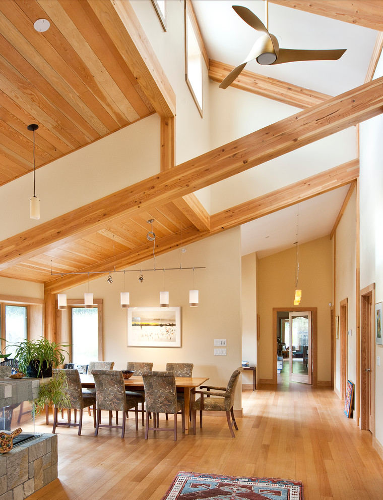 Cette image montre une salle à manger ouverte sur le salon design avec un mur beige et un sol en bois brun.