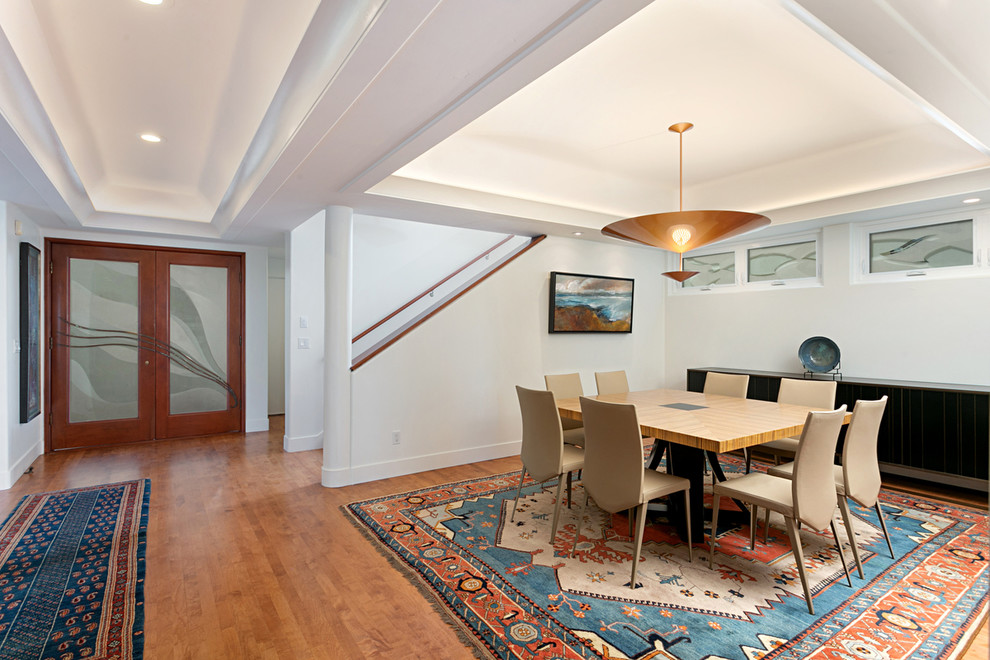 Idée de décoration pour une salle à manger ouverte sur le salon design de taille moyenne avec un mur blanc, un sol en bois brun et un sol marron.