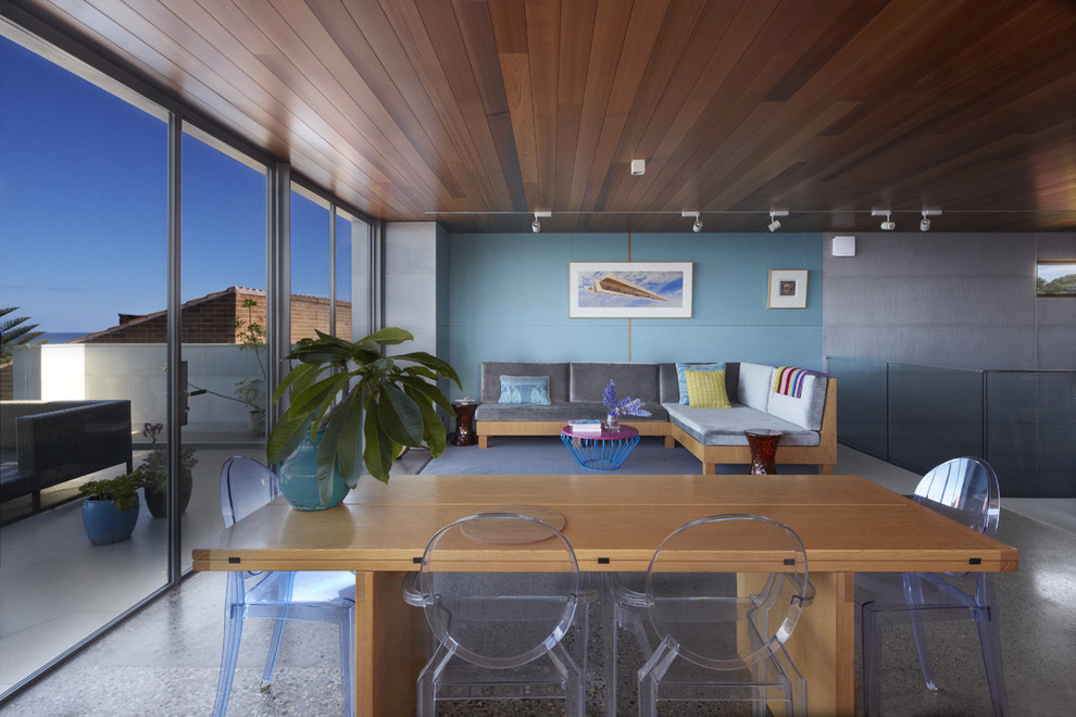This is an example of a contemporary dining room in Sydney with multi-coloured walls, concrete flooring and multi-coloured floors.