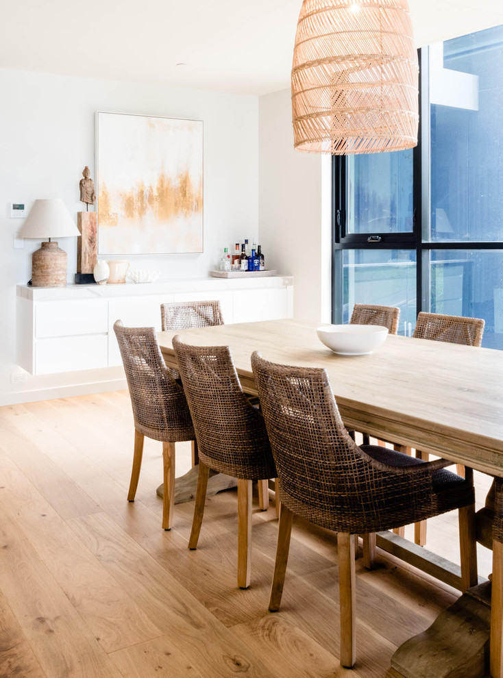 Foto di una sala da pranzo aperta verso il soggiorno stile marino di medie dimensioni con pareti bianche, pavimento in legno massello medio e pavimento marrone