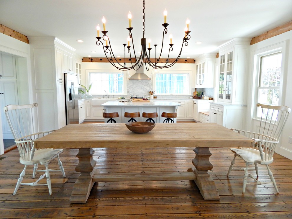 Cette image montre une grande salle à manger ouverte sur la cuisine rustique avec un sol en bois brun, un mur blanc et aucune cheminée.