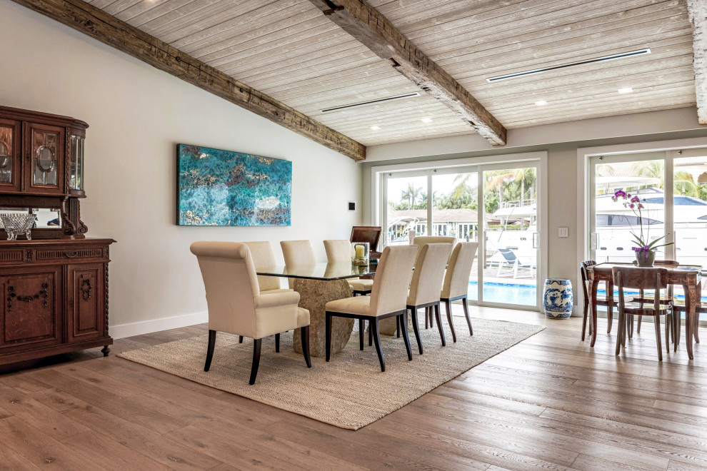 Immagine di una sala da pranzo aperta verso il soggiorno tradizionale con pareti grigie, pavimento in legno massello medio, pavimento marrone, travi a vista, soffitto a volta e soffitto in legno