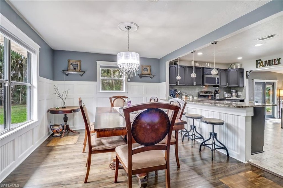 Foto di una sala da pranzo aperta verso la cucina tradizionale di medie dimensioni con pareti blu, pavimento in legno massello medio, nessun camino e pavimento marrone