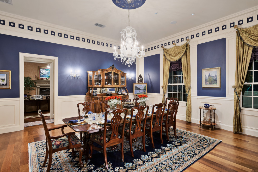 Cette image montre une salle à manger traditionnelle avec un mur bleu et un sol en bois brun.