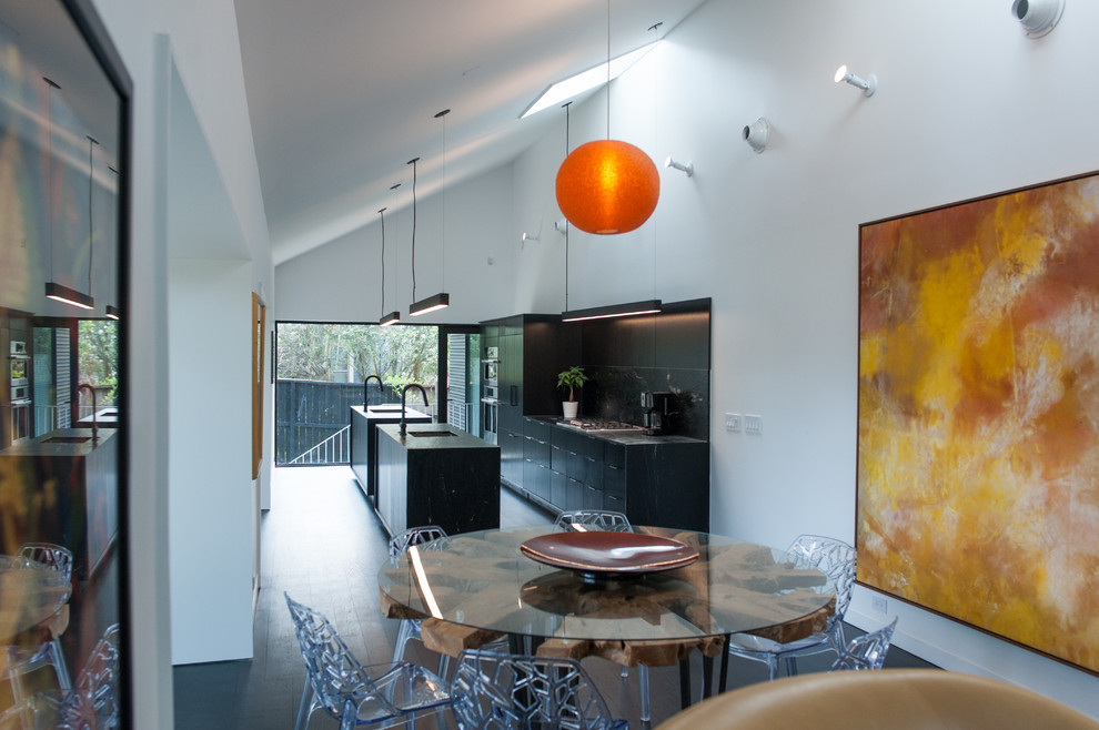 Foto di una piccola sala da pranzo aperta verso la cucina moderna con pareti bianche, parquet scuro e pavimento nero