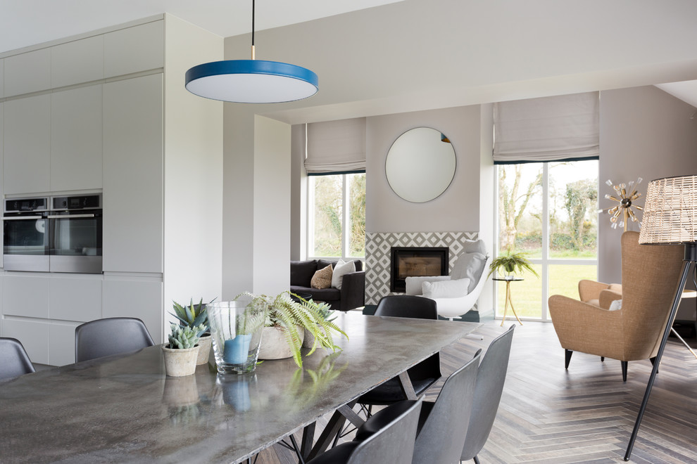 Идея дизайна: большая гостиная-столовая в современном стиле с серыми стенами, полом из керамической плитки, фасадом камина из плитки и коричневым полом