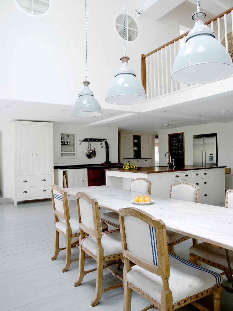 Cette photo montre une salle à manger ouverte sur la cuisine chic avec un mur blanc et parquet peint.