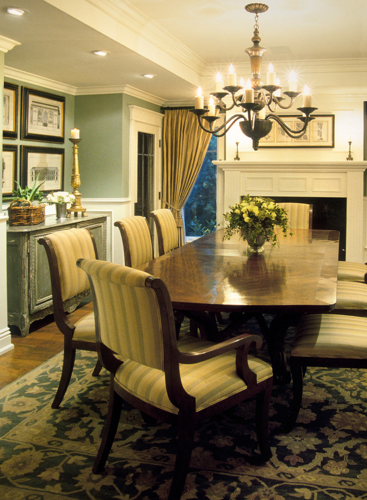 Aménagement d'une salle à manger classique fermée avec un mur vert, un sol en bois brun, une cheminée standard et un manteau de cheminée en bois.