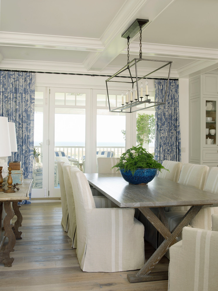 Design ideas for a large beach style open plan dining room in San Diego with white walls, light hardwood flooring and feature lighting.