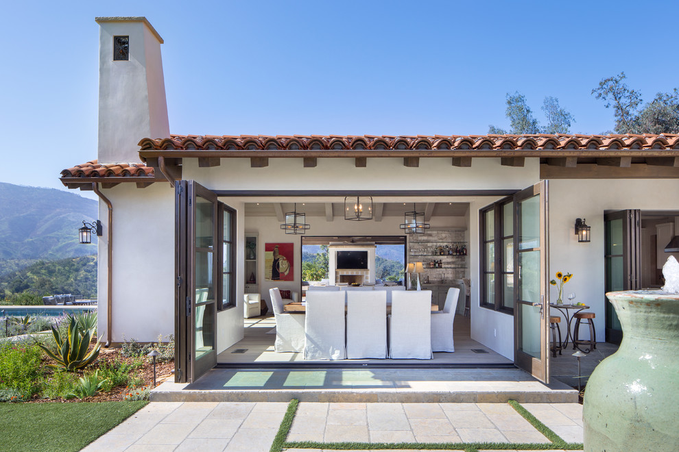 Example of a mid-sized tuscan beige floor and light wood floor great room design in Santa Barbara with white walls and no fireplace