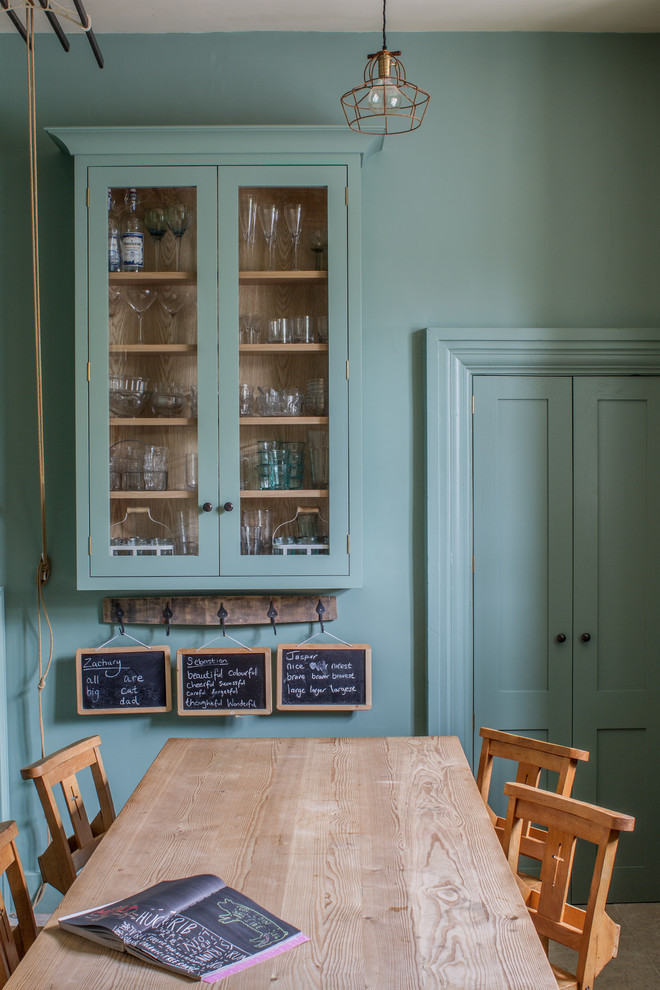 На фото: маленькая кухня-столовая в современном стиле с зелеными стенами и полом из известняка для на участке и в саду с