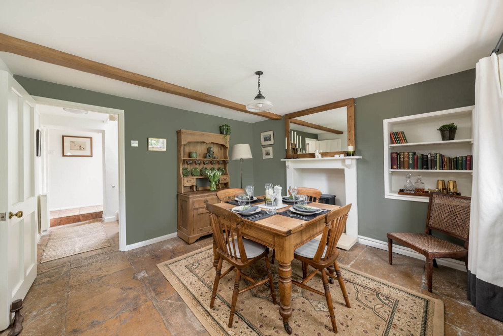 Стильный дизайн: отдельная столовая в стиле кантри с зелеными стенами, печью-буржуйкой, коричневым полом и балками на потолке - последний тренд