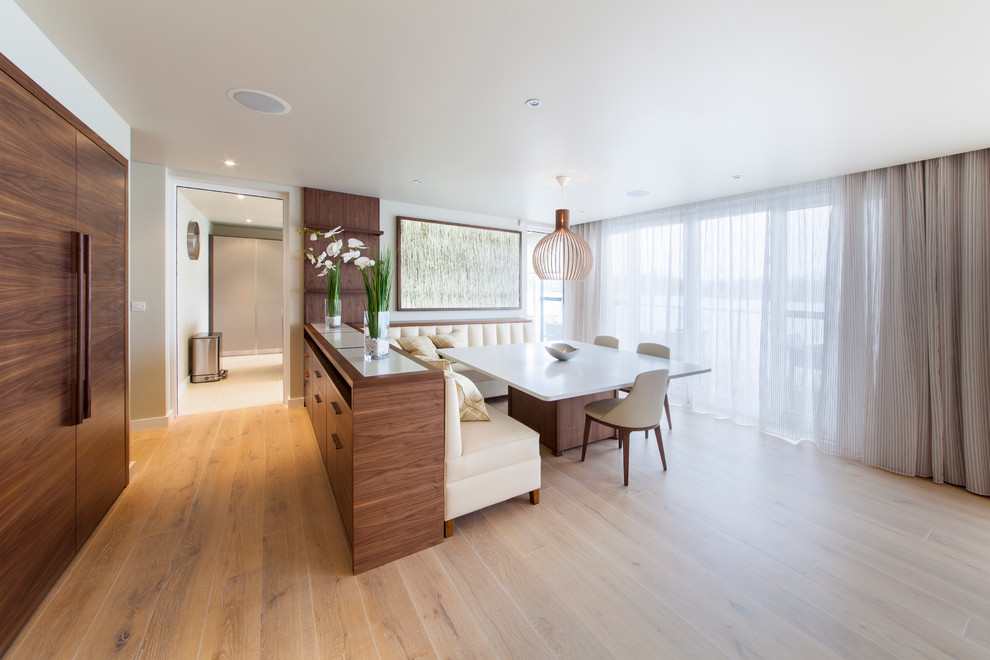 Contemporary dining room in Surrey with white walls, light hardwood flooring and feature lighting.