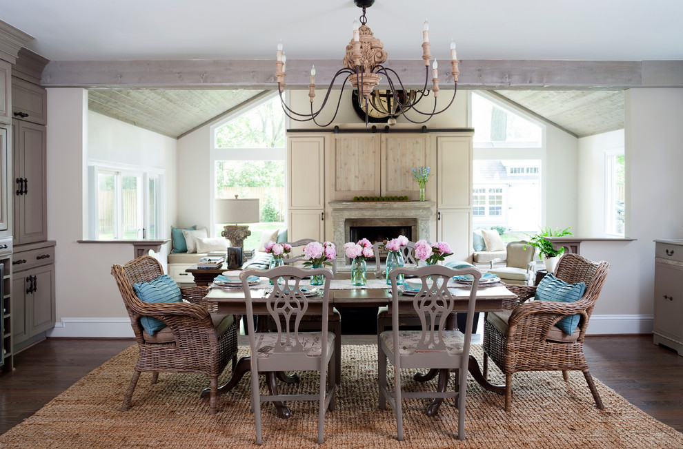 Immagine di una sala da pranzo aperta verso la cucina chic con pareti beige, parquet scuro e camino classico