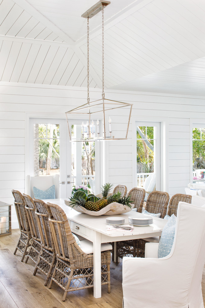 Beach style medium tone wood floor and brown floor dining room photo in Miami with white walls