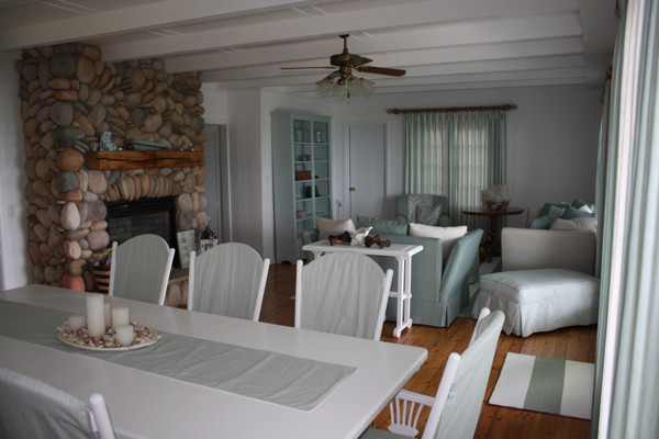Cette image montre une salle à manger ethnique avec un mur blanc, un sol en bois brun, une cheminée standard et un manteau de cheminée en pierre.